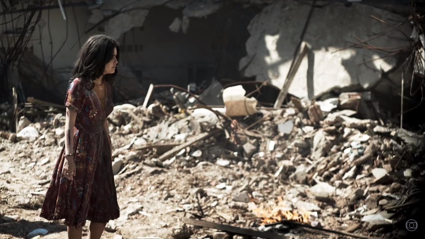 Laila (Julia Dalavia) meio a destruição de sua cidade em Órfãos da Terra