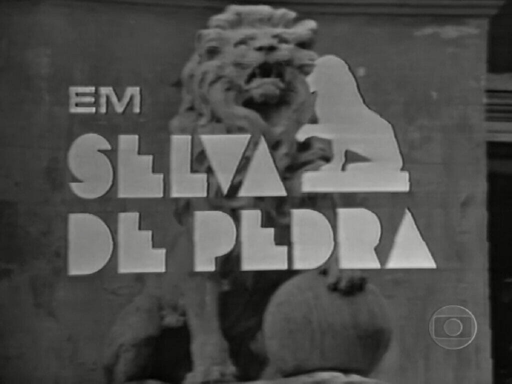 Logotipo da novela Selva de Pedra, de 1972, acompanhado do "em" dos créditos