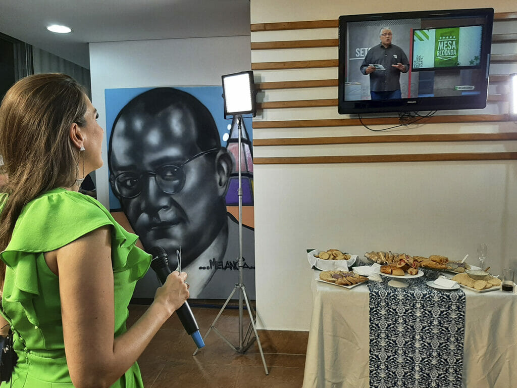 Michelle Gianella se prepara para entrar ao vivo no primeiro Mesa Redonda com Osmar Garraffa, diretamente da Sala VIP da Gazeta decorada com o retrato do jornalista Cásper Líbero